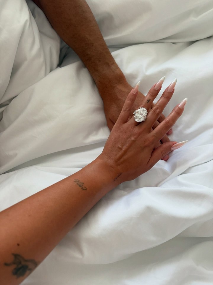 Close -up of the hands holding a large diamond ring.